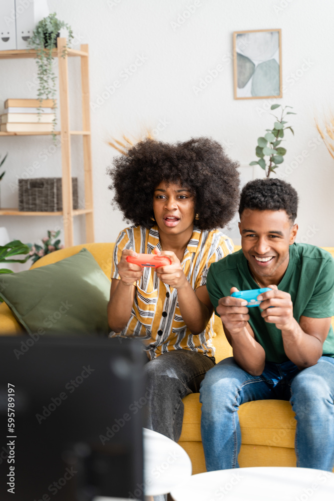 Multiethnic couple playing videogames on sofa