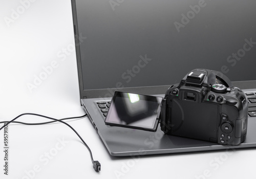 Aparat fotograficzny - lustrzanka cyfrowa z uchylonym ekranem stojąca na laptopie 