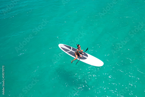 Canvas Print Aerial view of a woman on a white supboard in the turquoise waters of the Maldiv