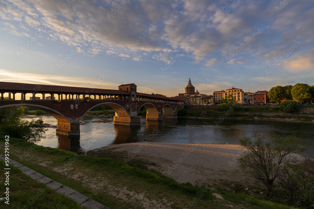 Skyline of Pavia , Ponte Coperto(covered bridge) is a bridge over the Ticino river in Pavia at sunset, Pavia Cathedral background, Italy