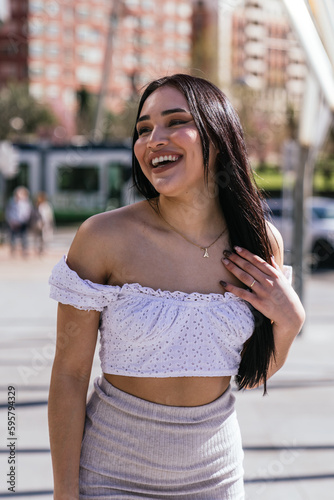 Sunny Street Style: Beautiful Latina Smiling in Modern Casual Attire with Tram in Background photo