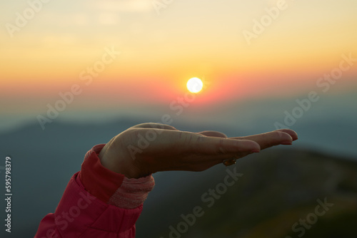 Sun over female hand. Sunrise in mountains. Ready for adventure. Natural mountain landscape with illuminated misty peaks, foggy slopes and valleys © Przemek Klos