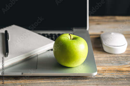 Apple near laptop at workplace, healthy snack.