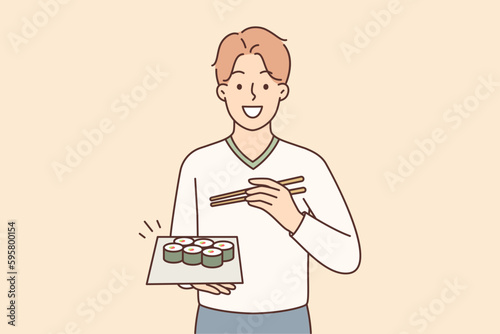 Man holding plate of maki rolls invites to dine in japanese restaurant with delicious healthy food