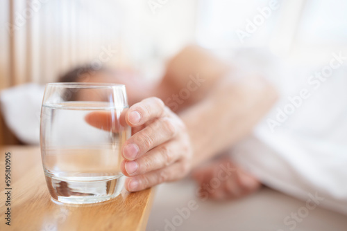 Glass of fresh drinking water on bed bedside table