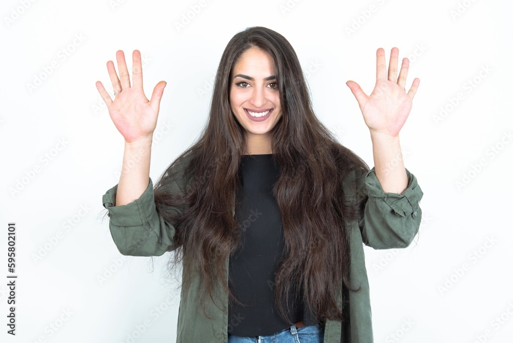 young brunette woman wearing casual clothes over white studio background showing and pointing up with fingers number ten while smiling confident and happy. young brunette woman wearing casual clothes over white studio background showing and pointing up with fingers number ten while smiling confident and happy.