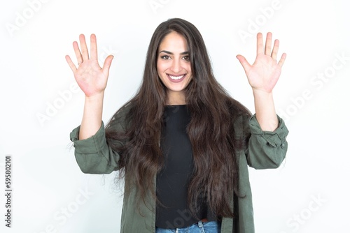young brunette woman wearing casual clothes over white studio background showing and pointing up with fingers number ten while smiling confident and happy. © Jihan