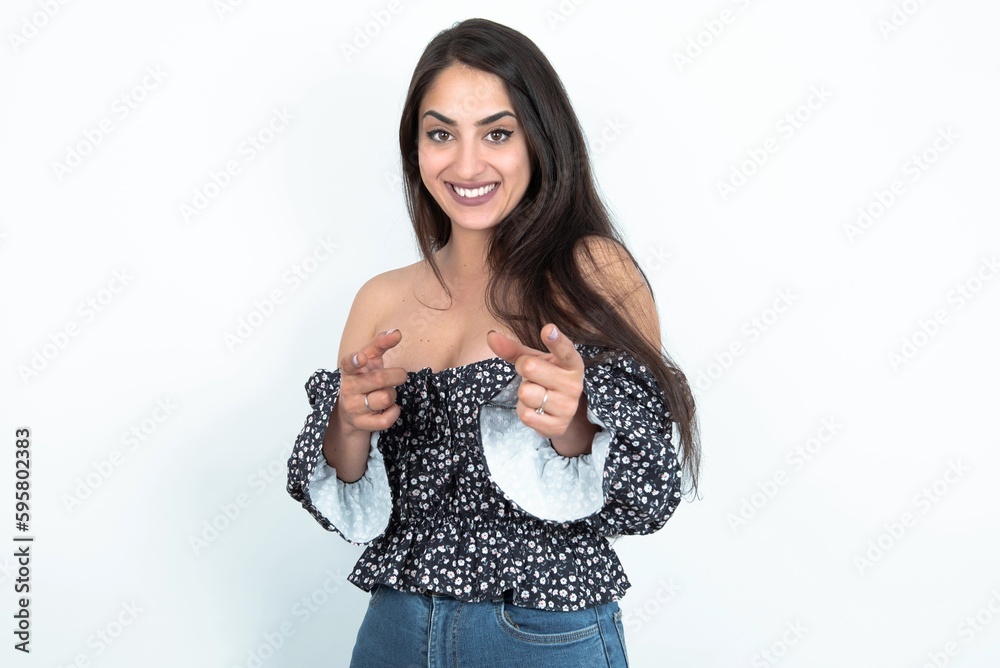 young brunette woman wearing a blouse over white studio background pointing fingers to camera with happy and funny face. Good energy and vibes. young brunette woman wearing a blouse over white studio background pointing fingers to camera with happy and funny face. Good energy and vibes.
