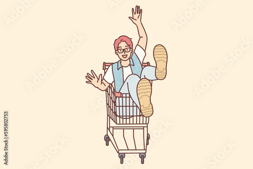 Cheerful man rides sitting in cart and supermarket after shopping and buying goods in store