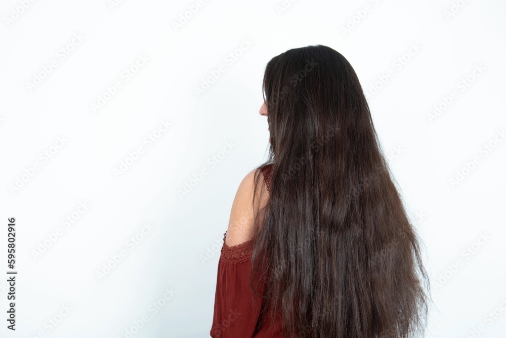 The back side view of a young brunette woman wearing red blouse over white studio background. Studio Shoot. The back side view of a young brunette woman wearing red blouse over white studio background. Studio Shoot.