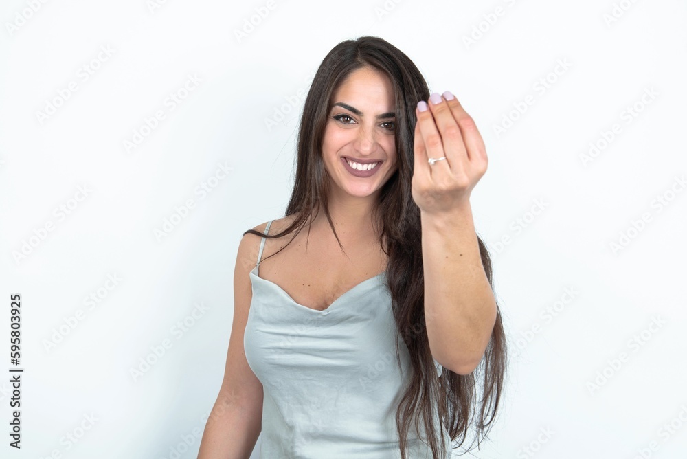 young brunette woman wearing white tank top over white studio background Doing Italian gesture with hand and fingers confident expression young brunette woman wearing white tank top over white studio background Doing Italian gesture with hand and fingers confident expression