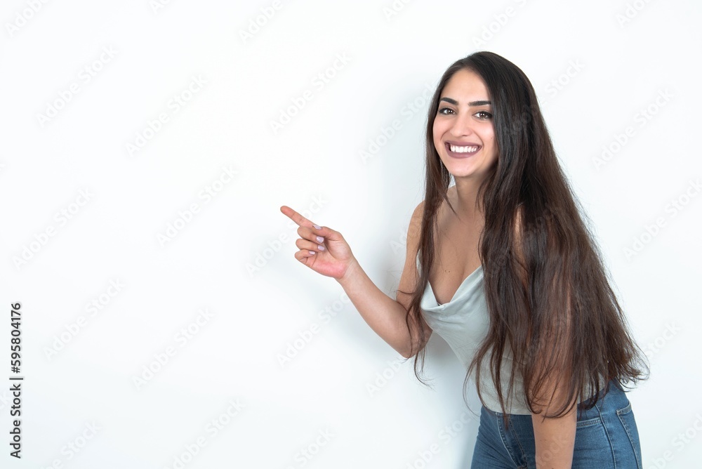 Profile photo of brunette woman wearing white tank top over white studio background indicate finger empty space offer Profile photo of brunette woman wearing white tank top over white studio background indicate finger empty space offer