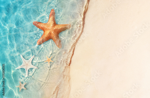Starfish on the sand beach in clear sea water. Summer background. Summer time .Copy space. Relaxing on the beach. © Belight