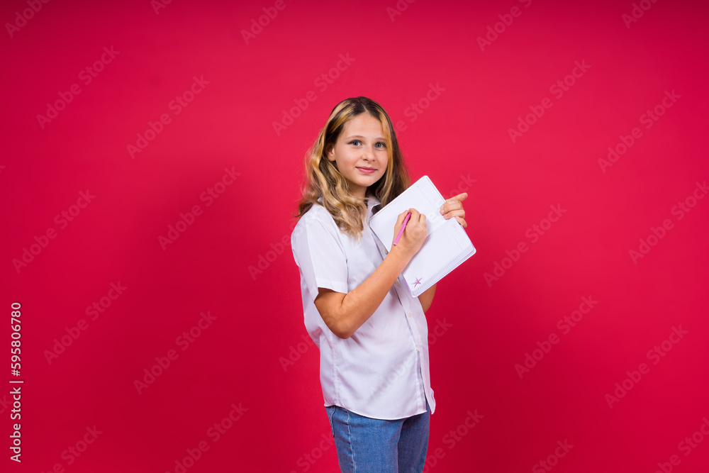 Portrait of positive little girl with notebook, looks smiling at camera, child doing homework Portrait of positive little girl with notebook, looks smiling at camera, child doing homework