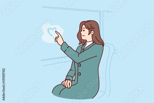 Woman passenger tram draws heart on glass, remembering beloved man and wishing to meet after separation. Girl in love depicts heart on steamy bus window, experiencing romantic feelings for boyfriend
