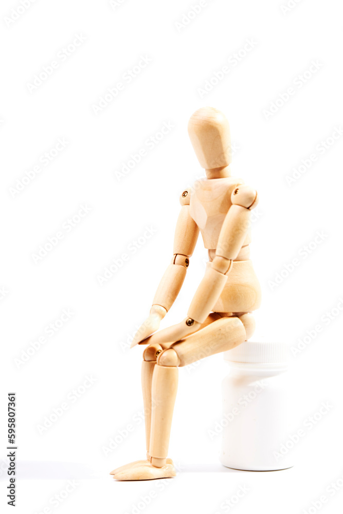 Depressed and sad dummy sitting on a bottle of pills on a white background. Concept of depression Depressed and sad dummy sitting on a bottle of pills on a white background. Concept of depression