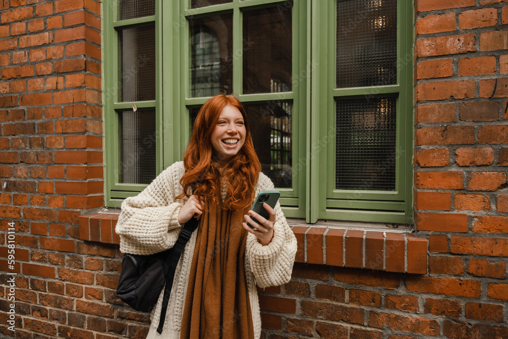 Naklejka premium Beautiful girl using mobile phone while standing outdoors