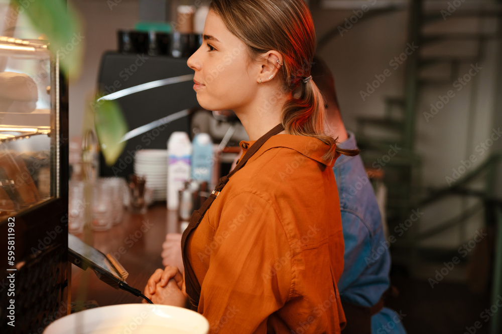 Woman barista smiling while standing at counter in coffee shop Woman barista smiling while standing at counter in coffee shop