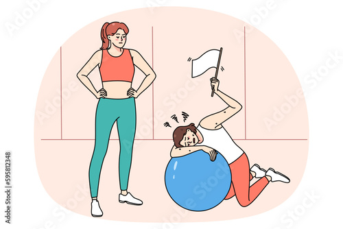 Tired woman rest lying on fitness ball after workout with personal trainer in sports club. Exhausted girl show white flag feel fatigue and weakness at sport training in gym. Sporty lifestyle.