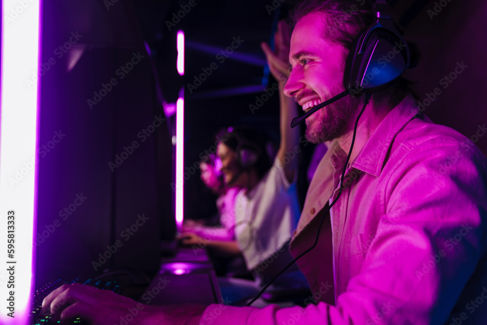 Team of gamers giving high five to each other while playing video game on championship in cybersport club Team of gamers giving high five to each other while playing video game on championship in cybersport club