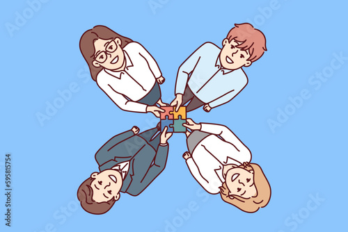 Friendly business people hold together puzzle symbolizing consolidation and synergy in performance of corporate tasks. Top view of men and women collaborating to increase business profits