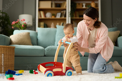 Joyful mother and baby boy playing with toys on a carpet at home photo