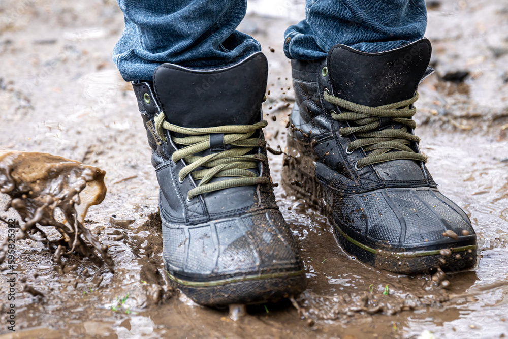 A man in jeans and boots walks through the swamp in rainy weather. A man in jeans and boots walks through the swamp in rainy weather.