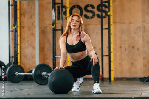 Front view. Sitting, barbell on the floor. Beautiful strong woman is in the gym