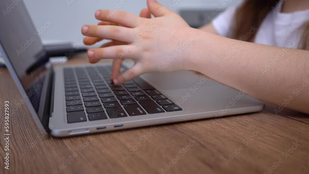 Close-up of little girl's hands typing on the laptop keyboard. Virtual learning. Close-up of little girl's hands typing on the laptop keyboard. Virtual learning.