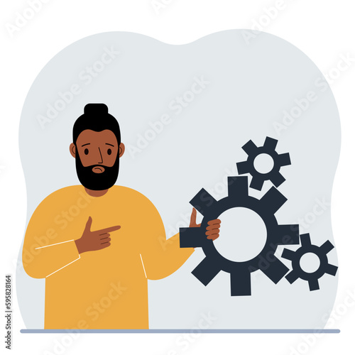 A man holds gears in his hand. Points a finger at the cogwheels. The concept of financial planning, movement, life, education or maintenance.