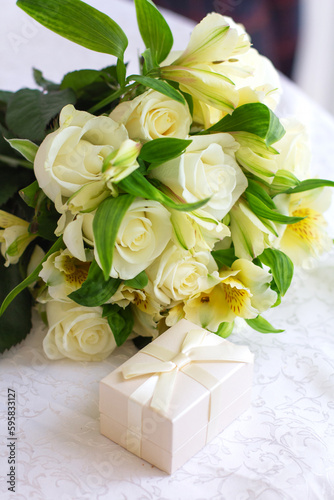 A bouquet of roses next to a white gift box