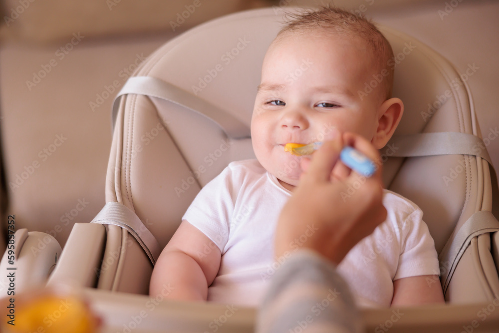 Baby boy sitting in high chair eating porridge Baby boy sitting in high chair eating porridge