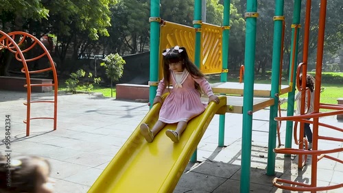 Cheerful children roll down the yellow slide on the playground