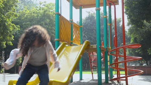 Happy kids playing on yellow slide in the park