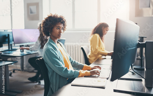 Young businesswoman and coworkers using computers at desks in an office