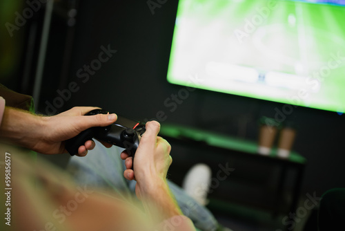 KYIV, UKRAINE - FEBRUARY 13, 2023: Cropped view of man playing video game near blurred tv in cyber club.