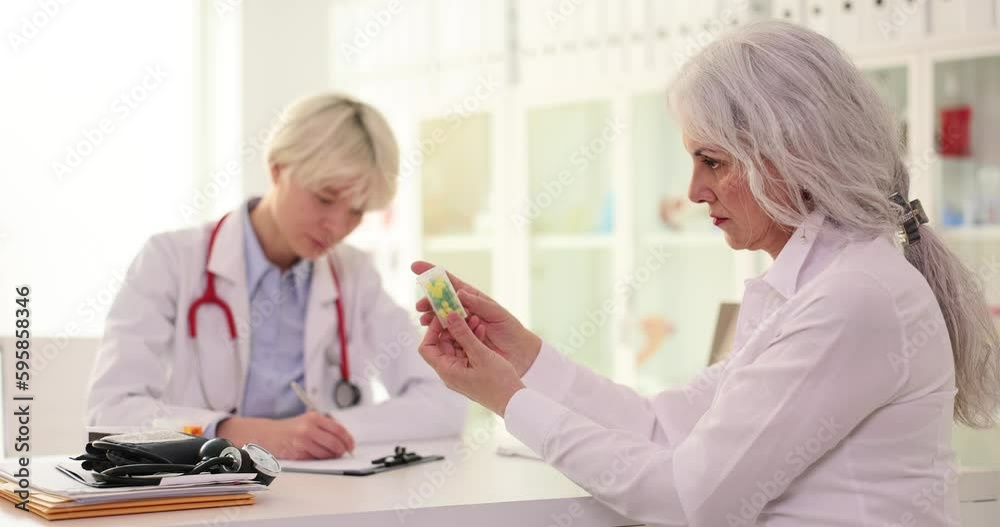 Doctor gives pills to elderly woman in clinic. Headache pills for old people