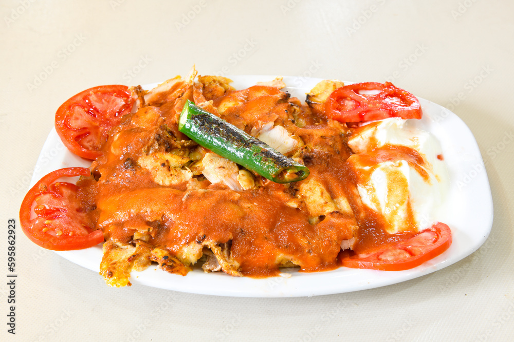 Traditional turkish iskender kebab in copper plate with yogurt, grilled tomatoes and fresh vegetables.