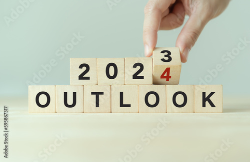 Economic outlook concept. Financial, business review or economic growth forecast for 2024. Turning OUTLOOK 2023 to 2024  text on wooden cube blocks. photo