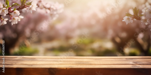 Empty wooden table in spring cherry orchard during sunny day. Spring background with empty wooden table. Natural template for product display with cherry blossoms bokeh and sunlight. 