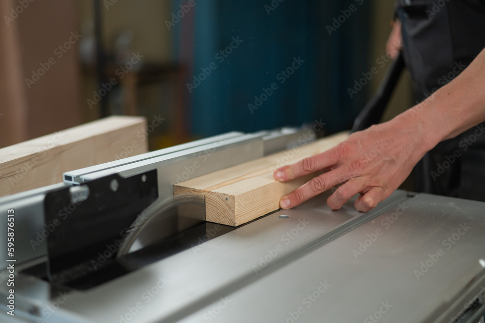 Close-up of a man cutting a wooden board on a circular machine. Close-up of a man cutting a wooden board on a circular machine.