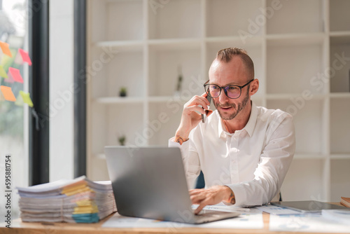 Businessman using laptop computer in office. Happy middle aged man, entrepreneur, small business owner working online.