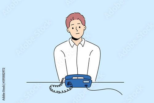 Unhappy man sit at desk look at landline phone waiting for someone call. Frustrated guy awaiting ring looking at corded telephone. Vector illustration. 