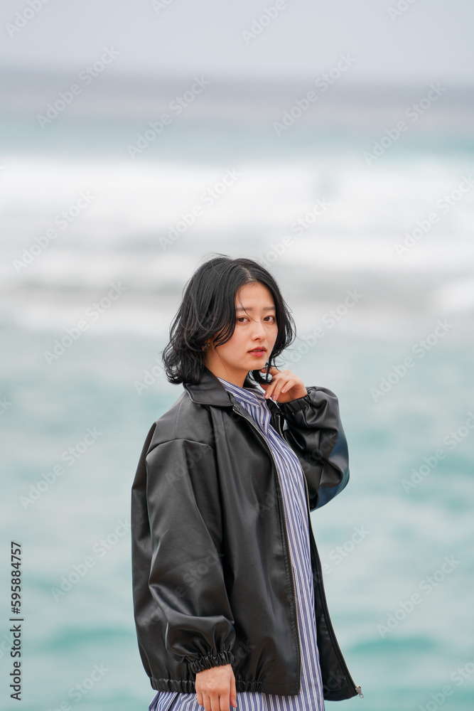 冬の沖縄の海を背景に潮風に吹かれる女性２
