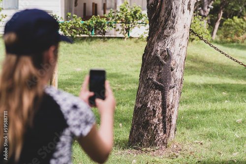 teen girl photographing a goanna on a tree photo