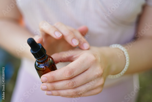 Woman holding glass bottle with spa cosmetic oil. salon therapy, natural eco body care products
