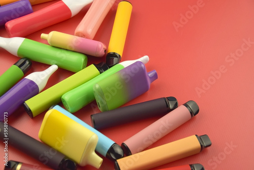 Set of multicolor disposable electronic cigarettes on a red background. photo