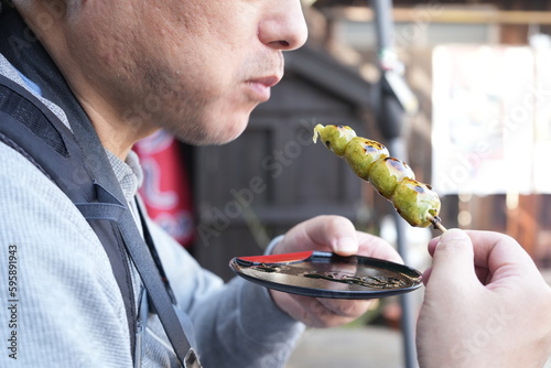 Japanese Food, Man eating Sticky Rice Cake Mochi, Skewered Ricecake Dumplings - 日本料理 和菓子 串だんご 草餅 食べる男性 photo
