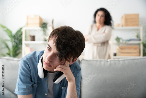 Fotografia Frustrated boy sitting on sofa and mother looking at him
