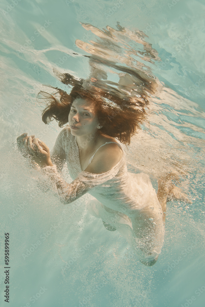 Portrait of a girl underwater in a white lace dress